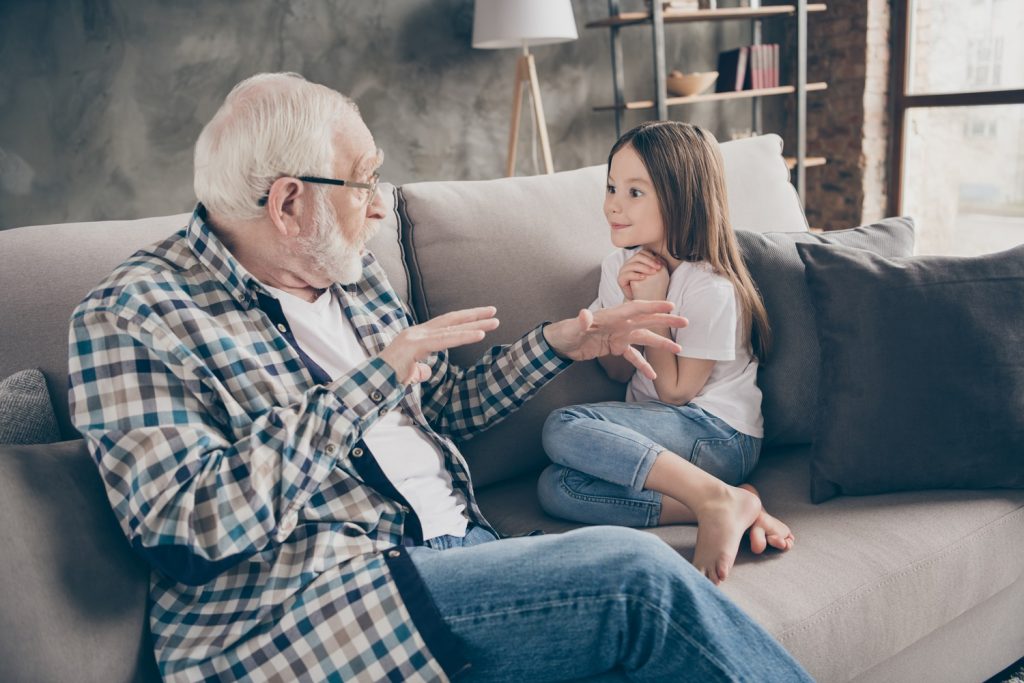 Photo of a grandfather telling a story to his granddaughter.